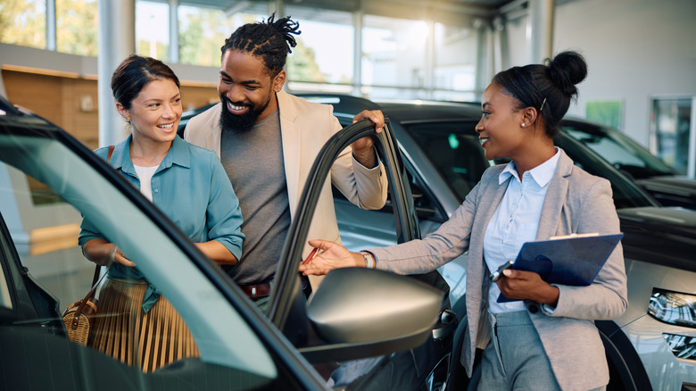 Couple looking at a new car with a salesperson