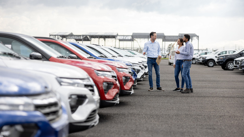 A Happy salesman showing cars to a couple at the dealership.