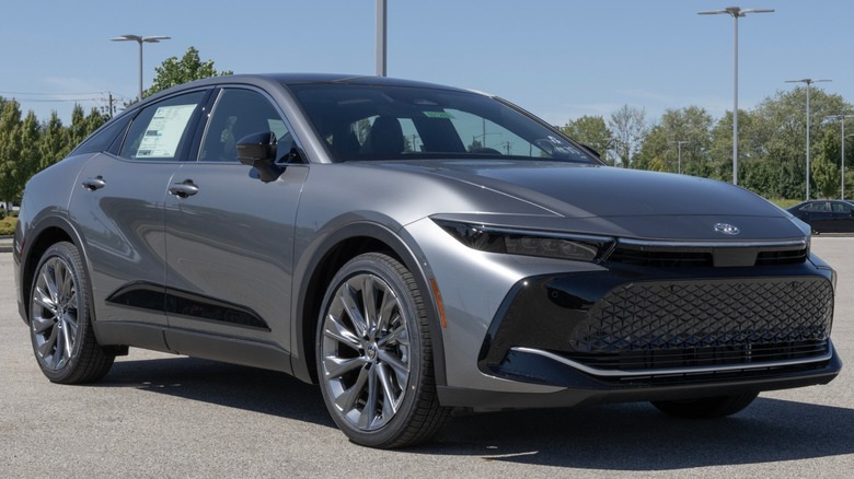 Gray Toyota Crown sedan parked outdoors, shown from a front three-quarter angle with a sleek grille, large wheels, and a raised ride height