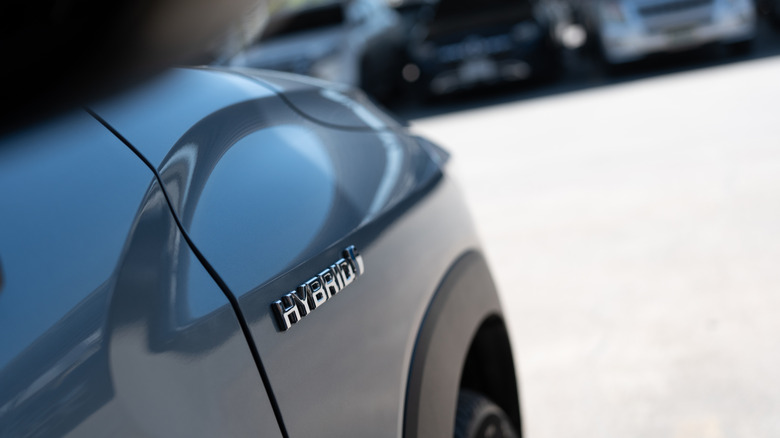 The word hybrid on the side of a grey sedan.