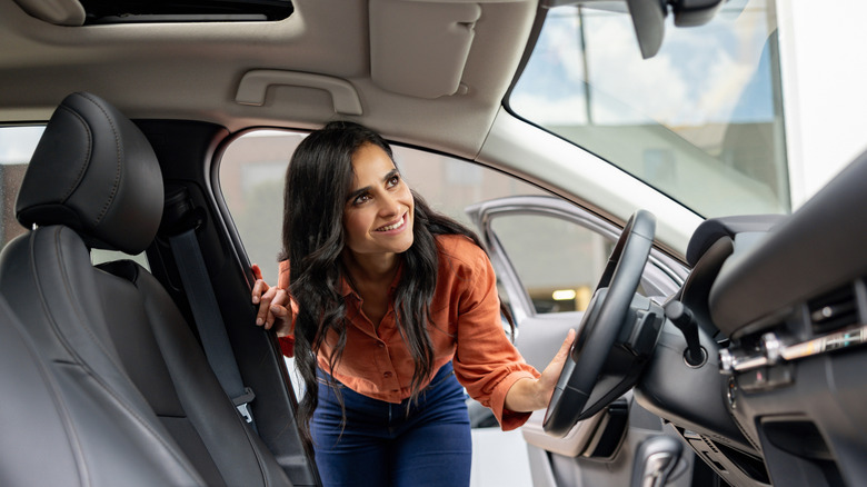 Smiling woman inspecting the interior of an SUV at a dealership