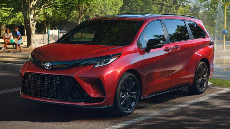 A red Toyota Sienna minivan parked outside at a playground.