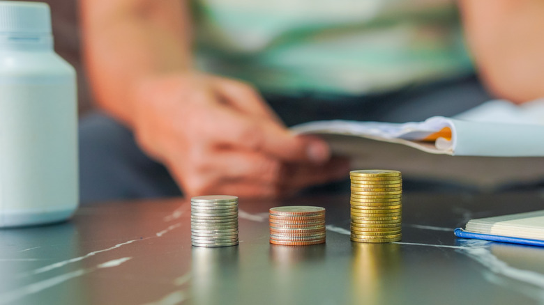 coins stacked up in front of person holding documents