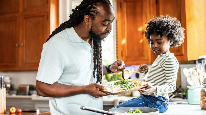 Father and young daughter cooking together in kitchen
