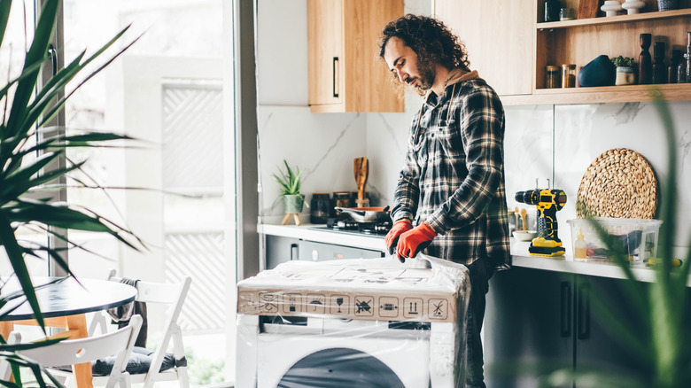 man opening packaging on new washing machine