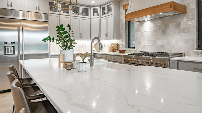 A white countertop with grey veining on an island in a kitchen.