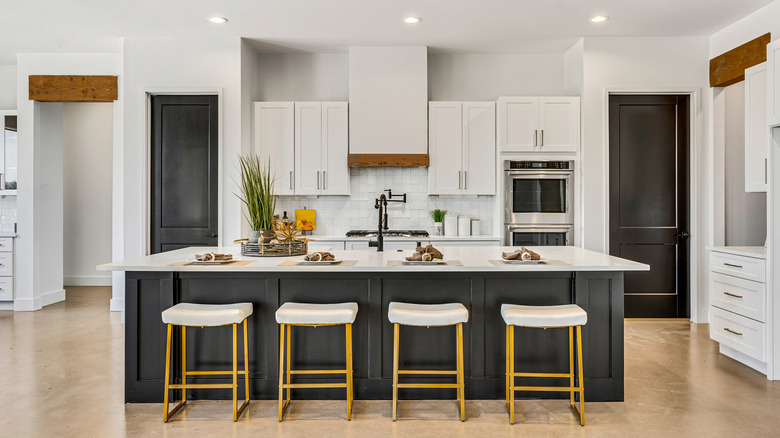 A kitchen with white cabinets and a black island