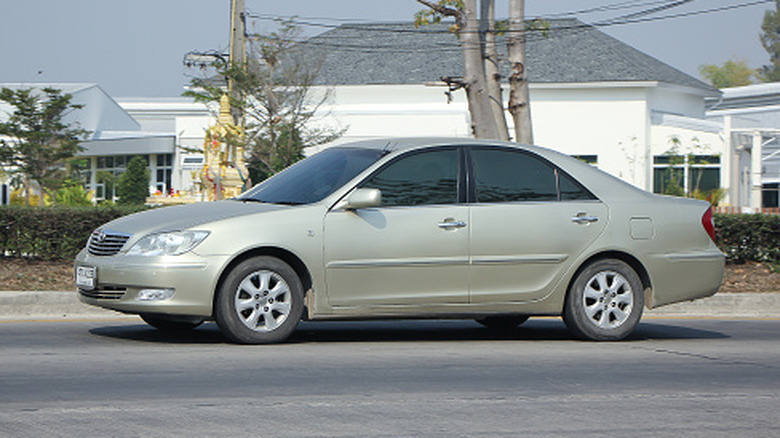 A tan Toyota Camry driving on the road.