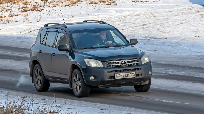 A black Toyota RAV4 driving on a snowy road.