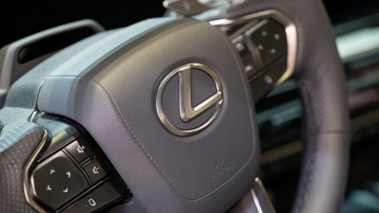 Close-up of a Lexus steering wheel with the silver Lexus emblem and control buttons