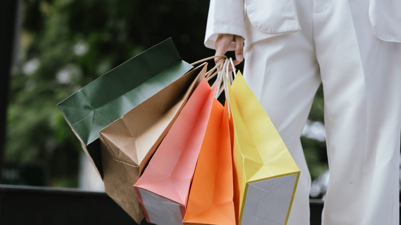Person holding multiple shopping bags.