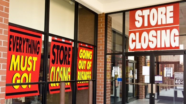 Multiple store closing signs posted in a retail store's windows and entrance.