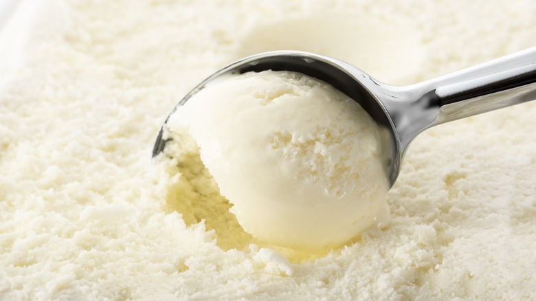 Vanilla ice cream getting scooped with a spoon.