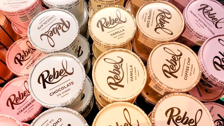 Pints of different flavors of Rebel ice cream stacked in rows in a reach-in freezer.