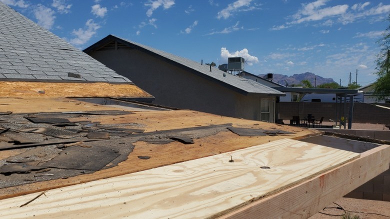 New boards replacing a damaged roof on a sunny day.