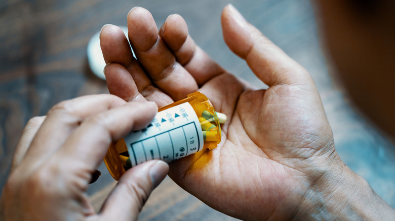 A person dispensing prescription drugs from a container