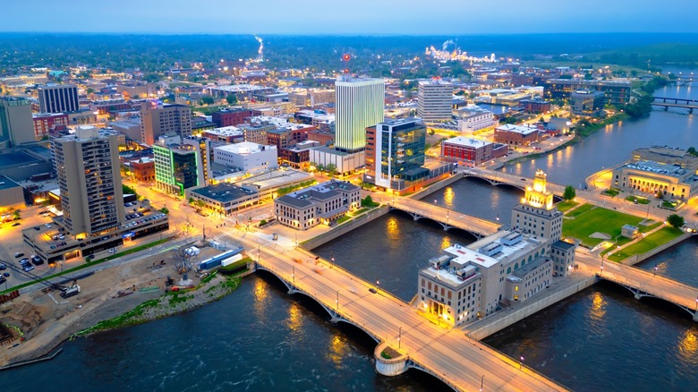 Nighttime riverfront view of Cedar Rapids, Iowa with city buildings and bridge lights reflecting on the water