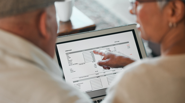 Couple reviewing budget document on a laptop screen.