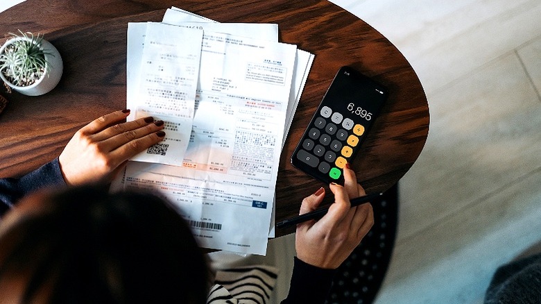Person budgeting expenses on calculator