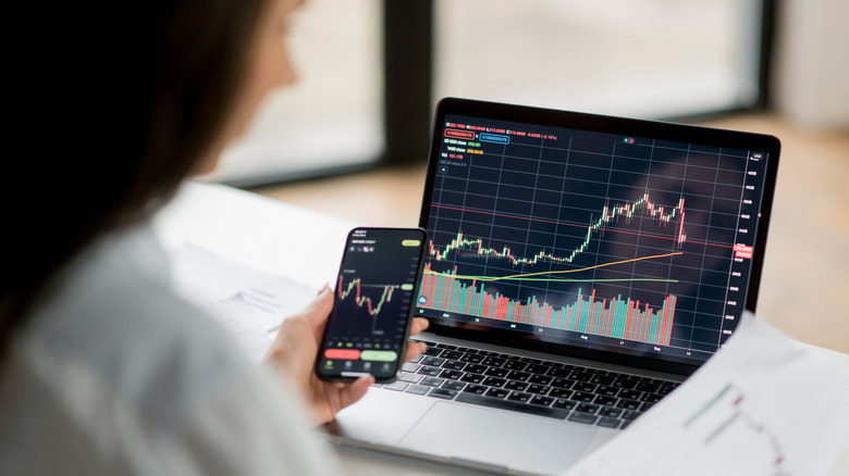 Woman comparing investment returns on a laptop and smartphone