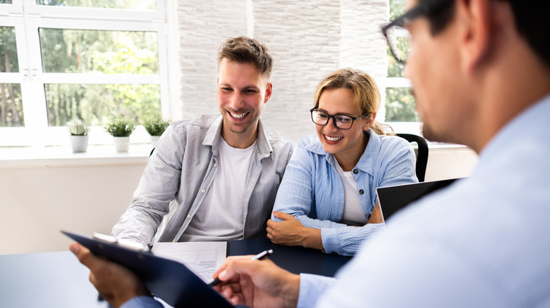 Financial consultant explaining new project investment to young couple in office