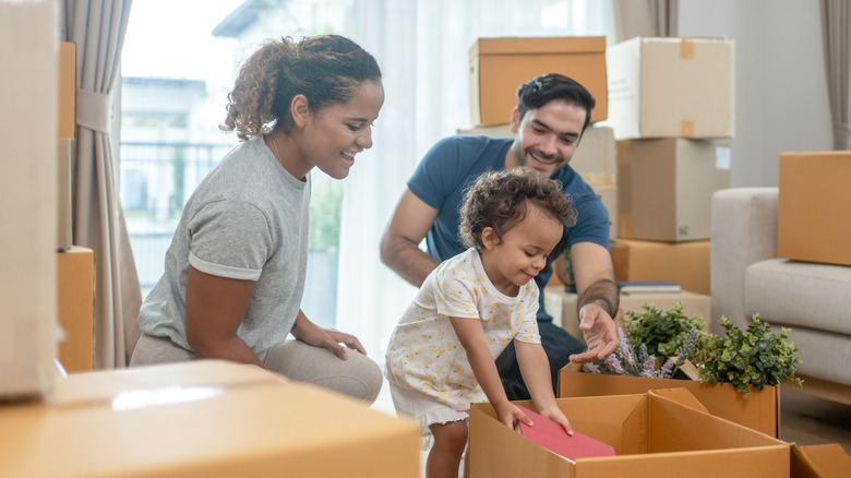 young parents and a child unpacking boxes in their new home