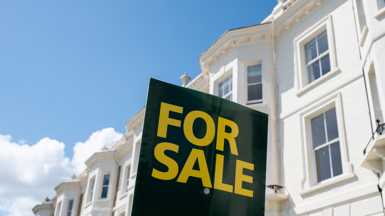 A 'for sale' sign in front of a row of rowhomes