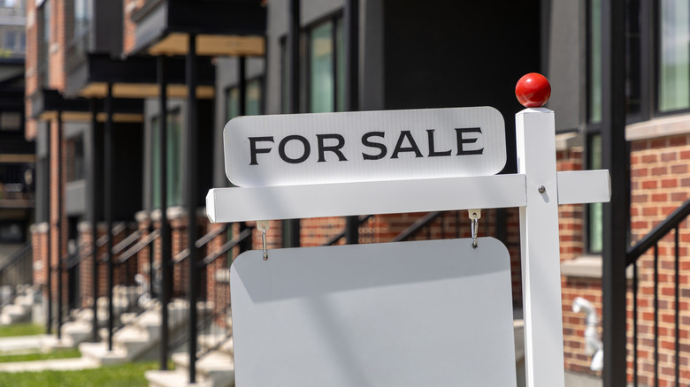 White for sale sign in front of brick housing