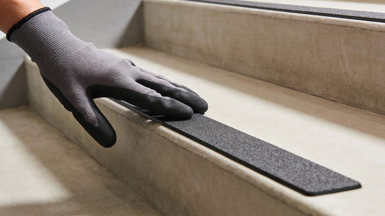 Gloved hand adds strip to stairs for better traction
