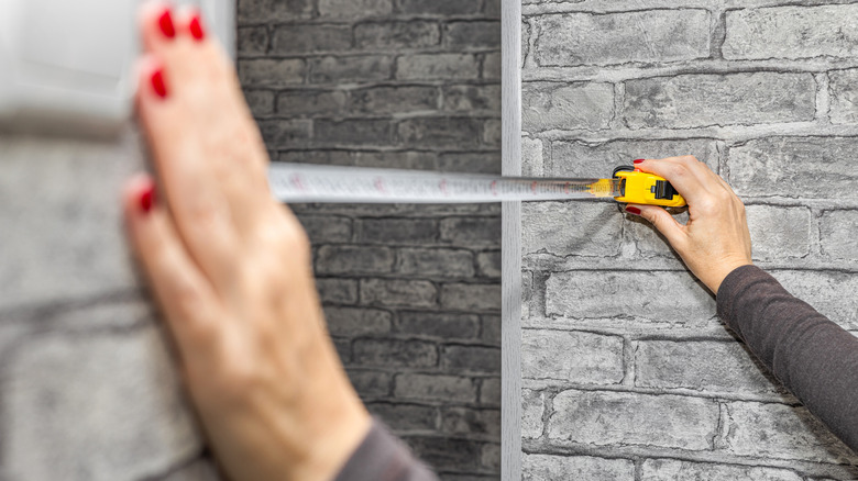 Hands of woman measuring a doorway with tape measure