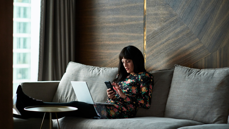 A woman looking at her smartphone on a couch
