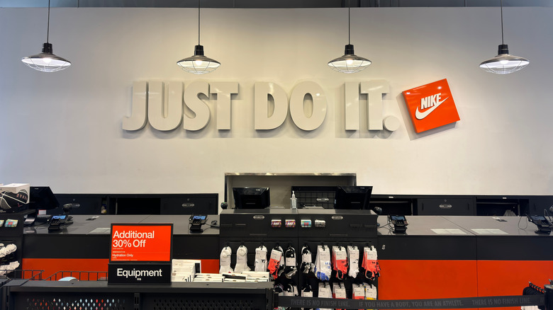 "Just Do It" on the wall behind a cash desk in a Nike store