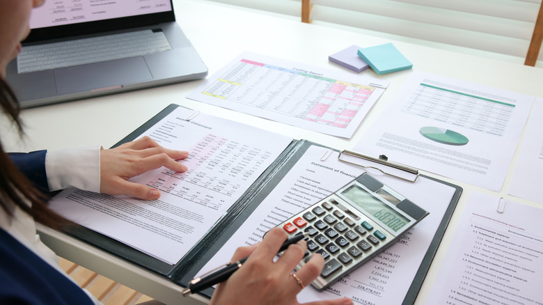Tax documents spread out with a woman using a calculator