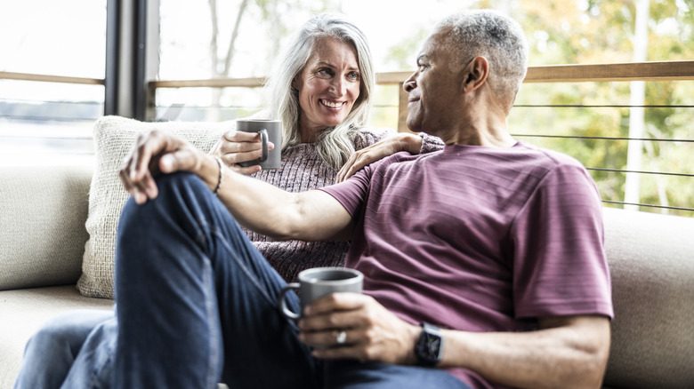 Senior couple having coffee and embracing on back porch of vacation home