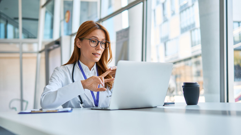 A doctor using a laptop while making gestures