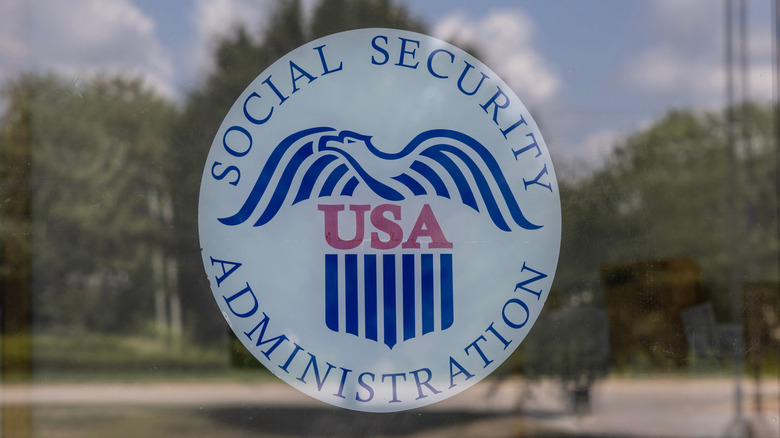 A round Social Security Administration sign on a glass door, on a sunny day