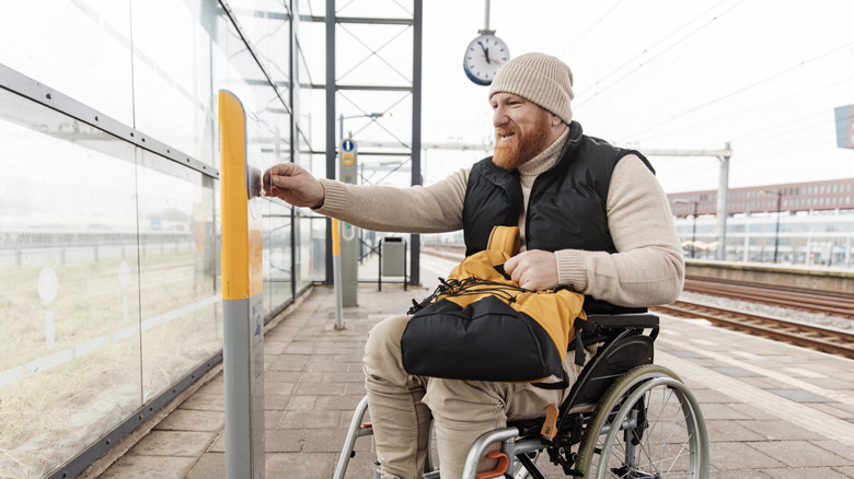 Man in wheelchair pushing a button