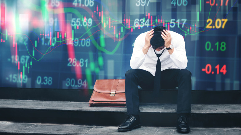 An investor looking forlorn against a backdrop of graphics reflecting a financial crash