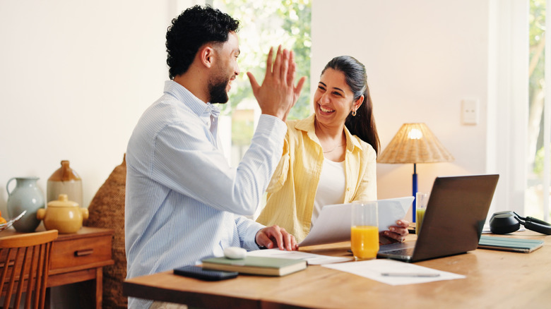 Couple slapping one another five in front of their laptop