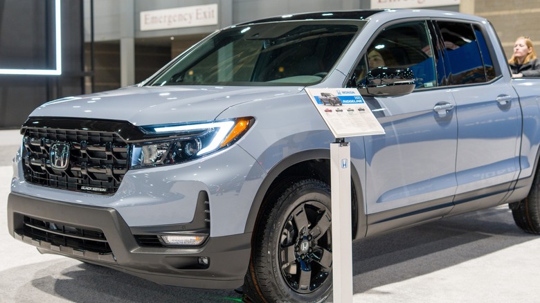 Gray Honda Ridgeline pickup displayed beside an information stand at an indoor auto show