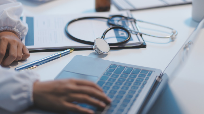 A person using a laptop with medical equipment next to them