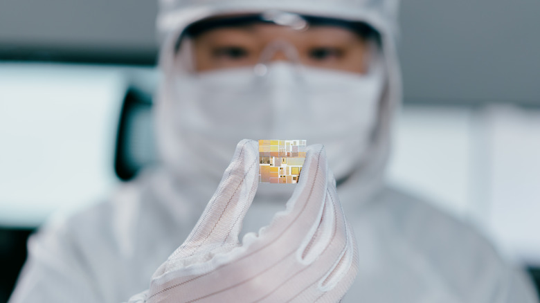 A worker in a semiconductor facility holding and inspecting a new microchip