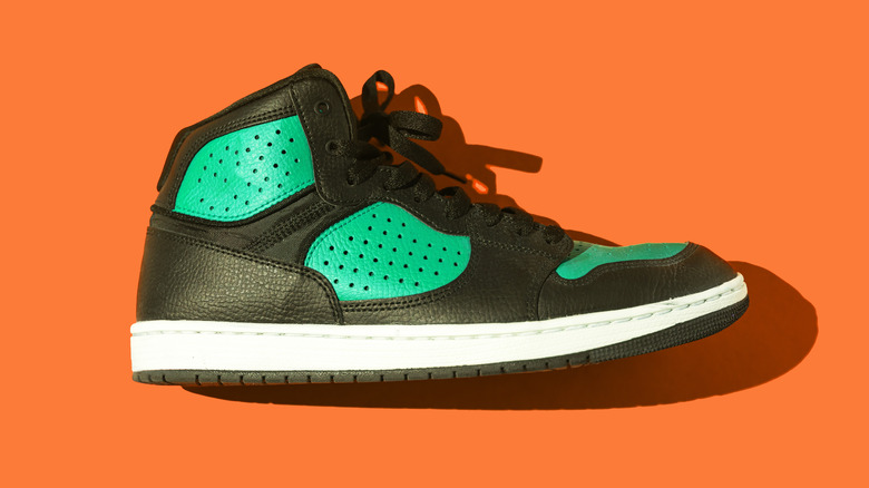 Black and green basketball sneakers, on a orange background.