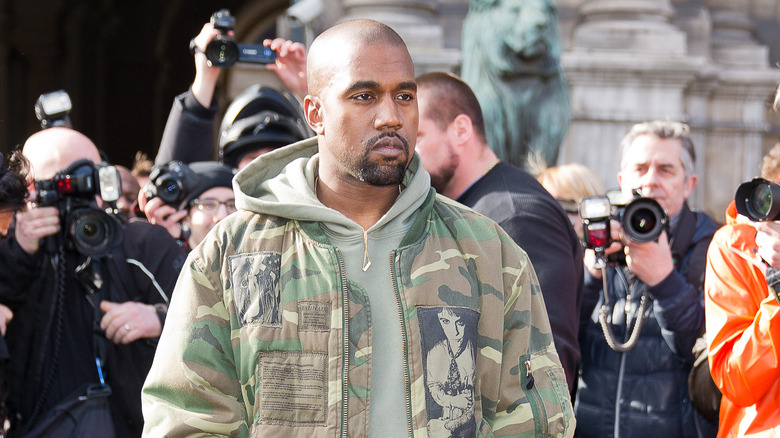 Kanye West posing for photographers in front of the Dries van noten fashion show.