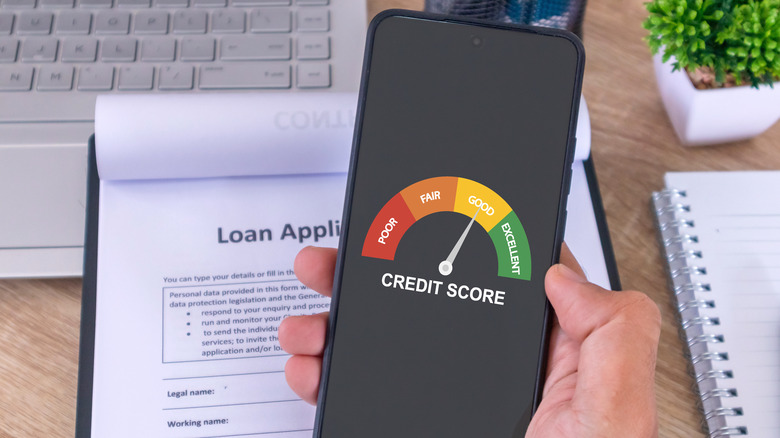 A hand holding a cellphone to check his credit score to apply for a loan to the bank