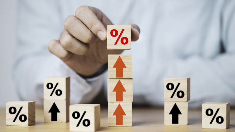 A hand putting percentage sign on three blocks of arrows that point up