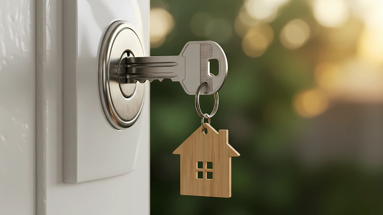 Close up of key with house-shaped keychain in open front door