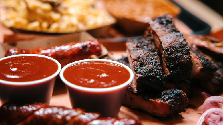 heaping plate of barbecue ribs, sauces, sausage, and sides