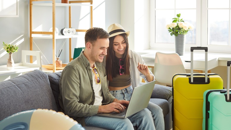 Young couple planning a trip on laptop at home