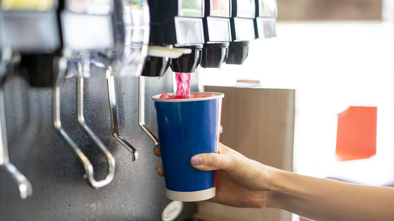 A person pours a fizzy drink, sparkling water, or cool ice soft drink
